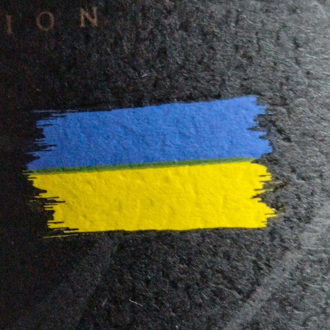 Detail shot of a Ukrainian flag on a black label on a red wine bottle.