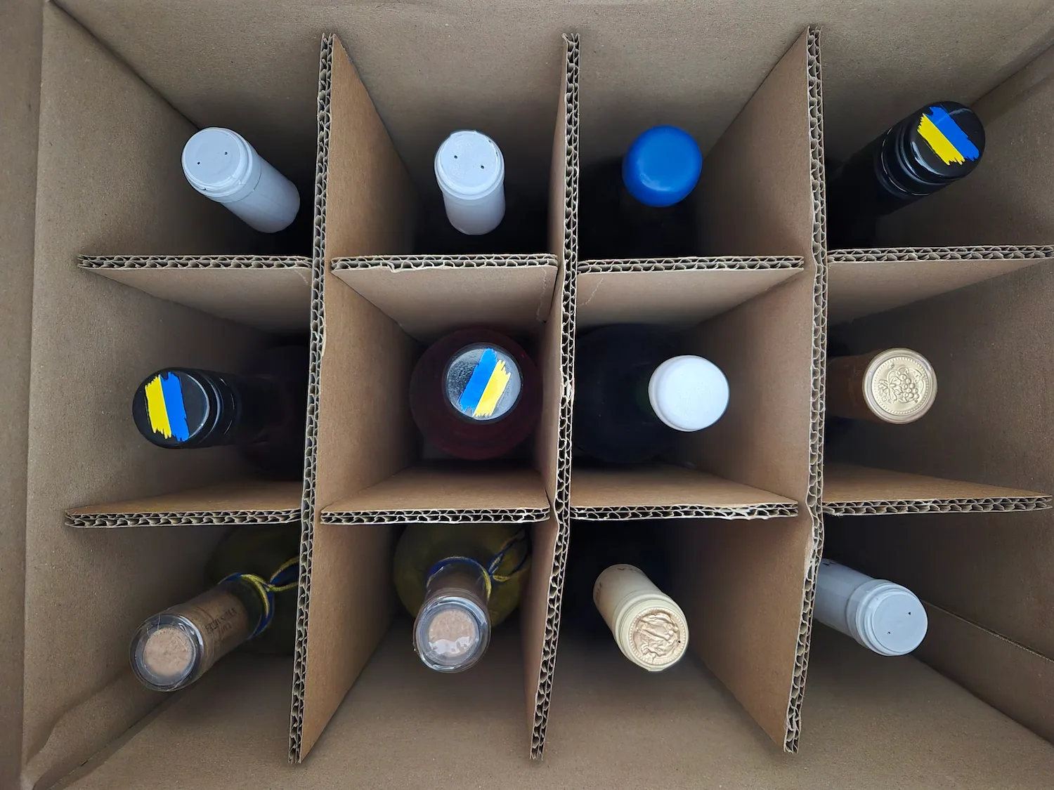 Many bottles of Ukrainian wine in a box, ready for the tasting. Some bottles feature the Ukrainian flag at the top. 🇺🇦