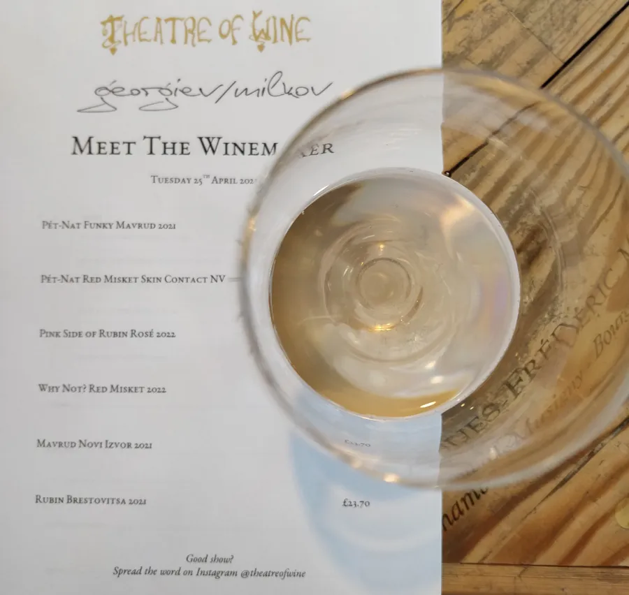 A glass of white wine on the table at Theatre of Winew in Tufnell Park, London, with a printout with the list of wines for the tasting in the background.'
